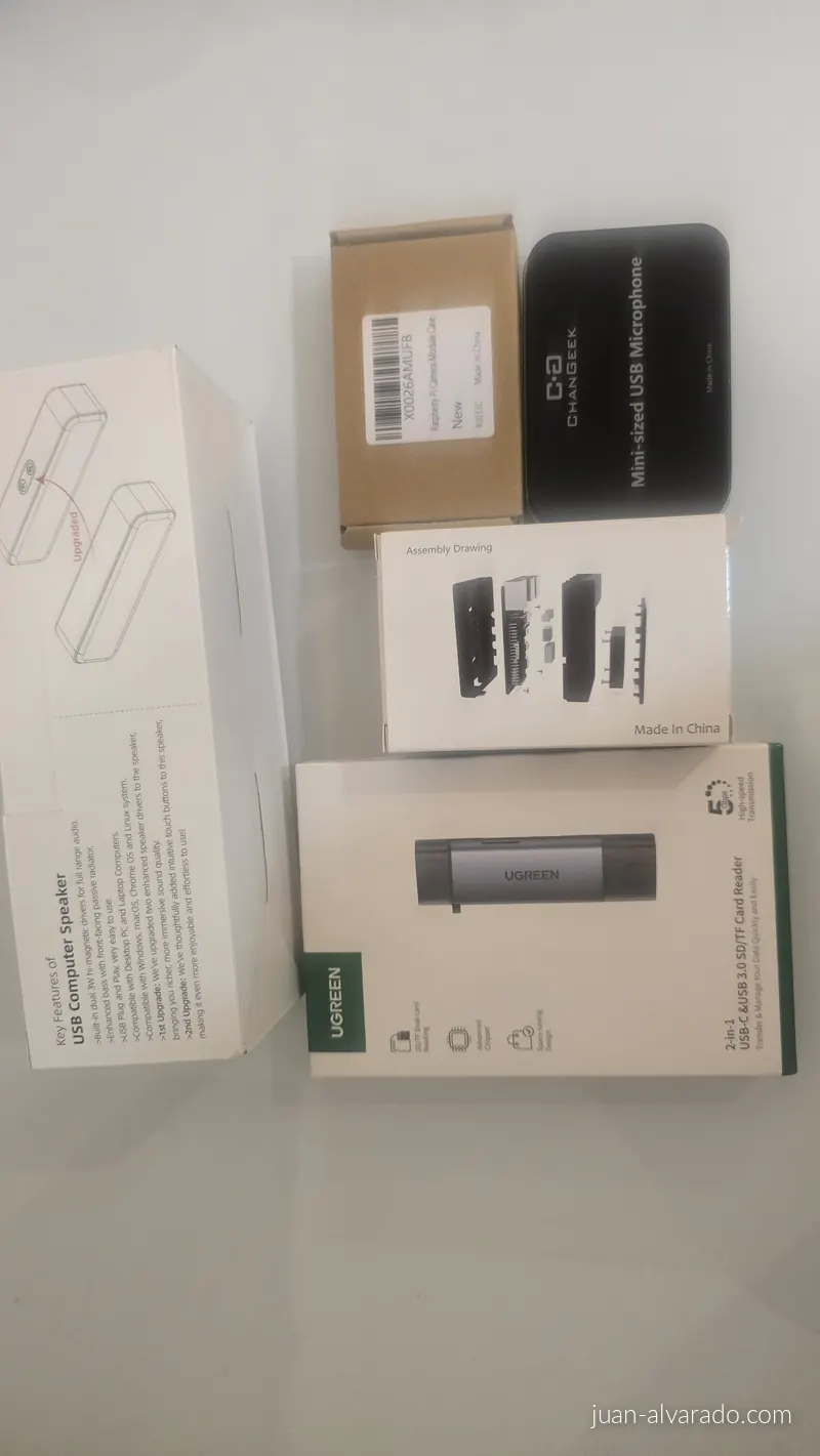 Unboxed parts: USB speaker, USB microphone, camera case, Pi case and an SD card reader
